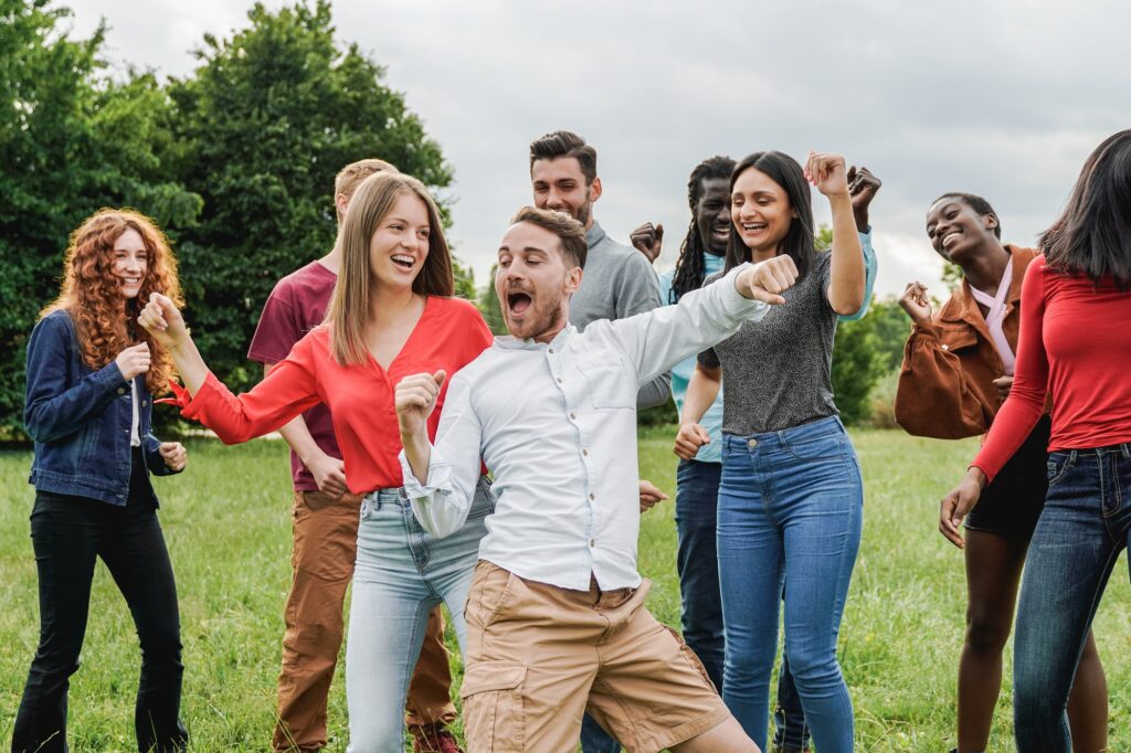 Multiethnic group of friends having fun dancing together outdoor during summer vacations